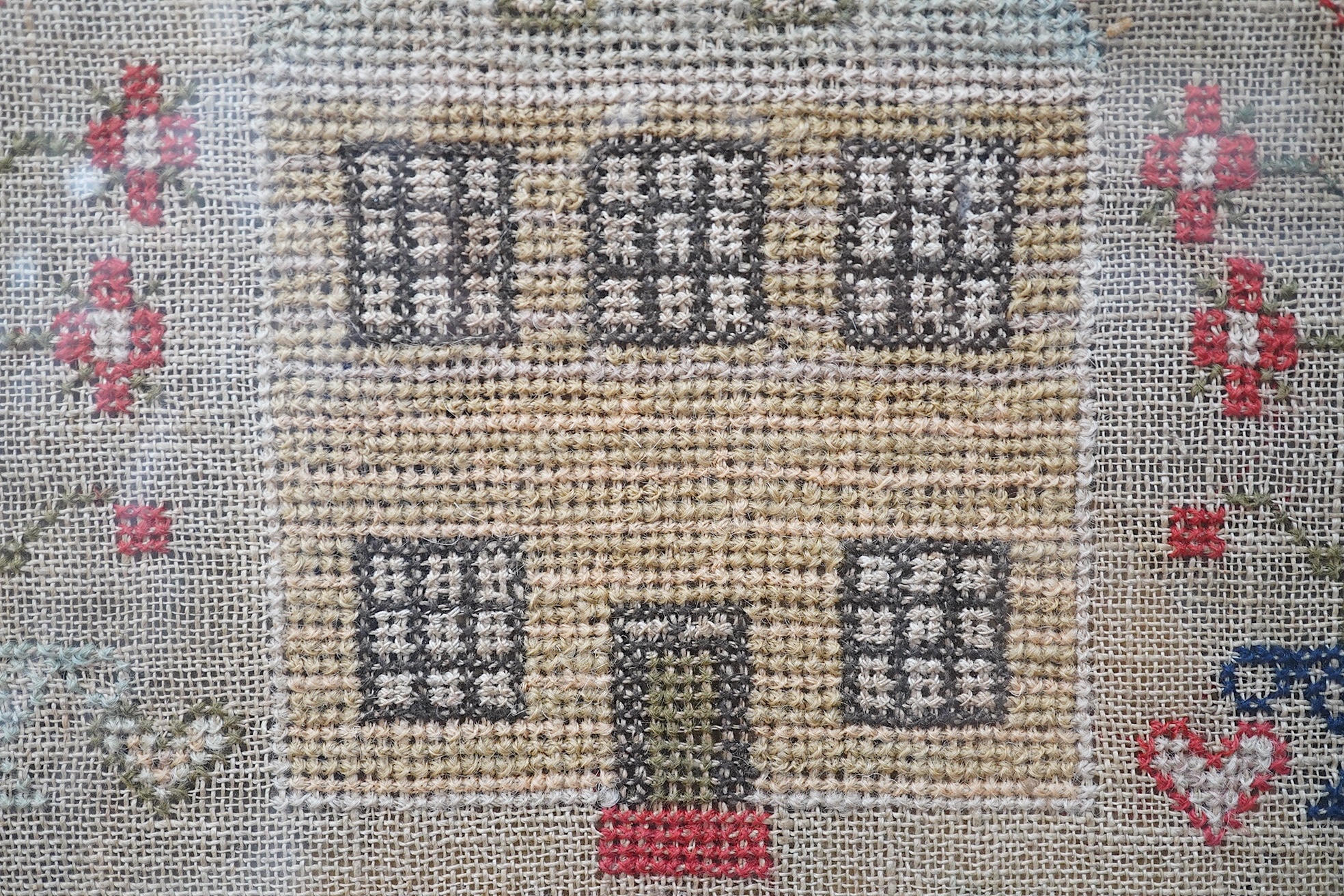 A large framed cross stitch sampler, by Helen Rae, dated 1851, worked mostly in red and green, with an ornate floral border around alphabet letters and numerals, large button hole letters and motifs, with a large central